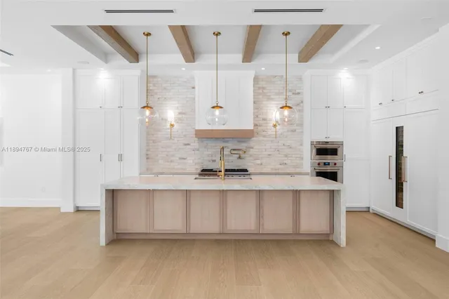 a large white kitchen with a sink and dishwasher a refrigerator with wooden floor