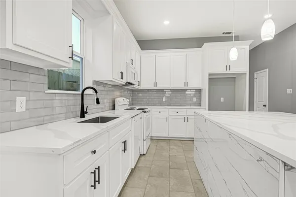 a kitchen with white cabinets appliances and a sink