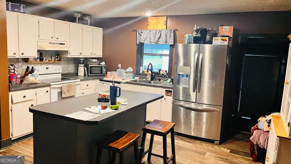 a kitchen with stainless steel appliances a refrigerator a sink a stove a table and chairs