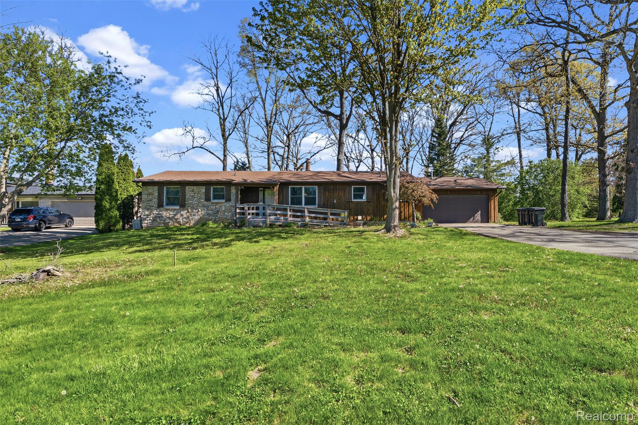 4191 McCandlish Road Grand Blanc, MI 48439 - Photo 4 of 53 Ranch-style home with a garage, a front yard, driveway, stone siding, and a wooden deck