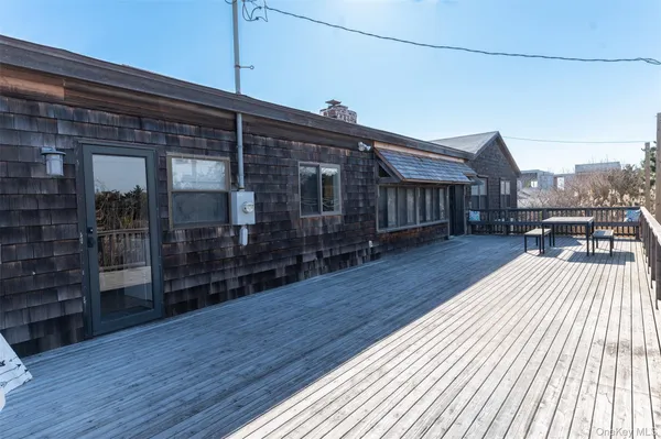 a view of sitting area on roof with wooden floor and fence