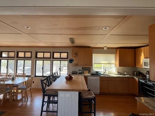 a kitchen with stainless steel appliances kitchen island granite countertop a table chairs in it and wooden floors