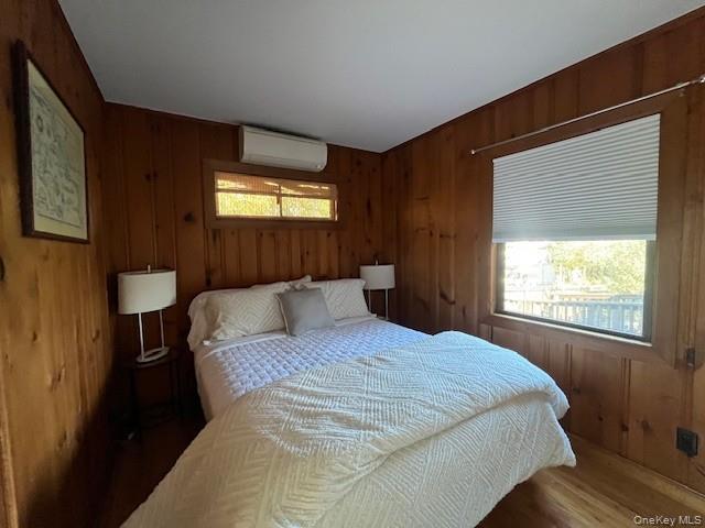 35 Sloop Walk Ocean Beach, NY 11770 - Photo 8 of 21 Bedroom featuring wood walls, wood finished floors, and a wall mounted air conditioner