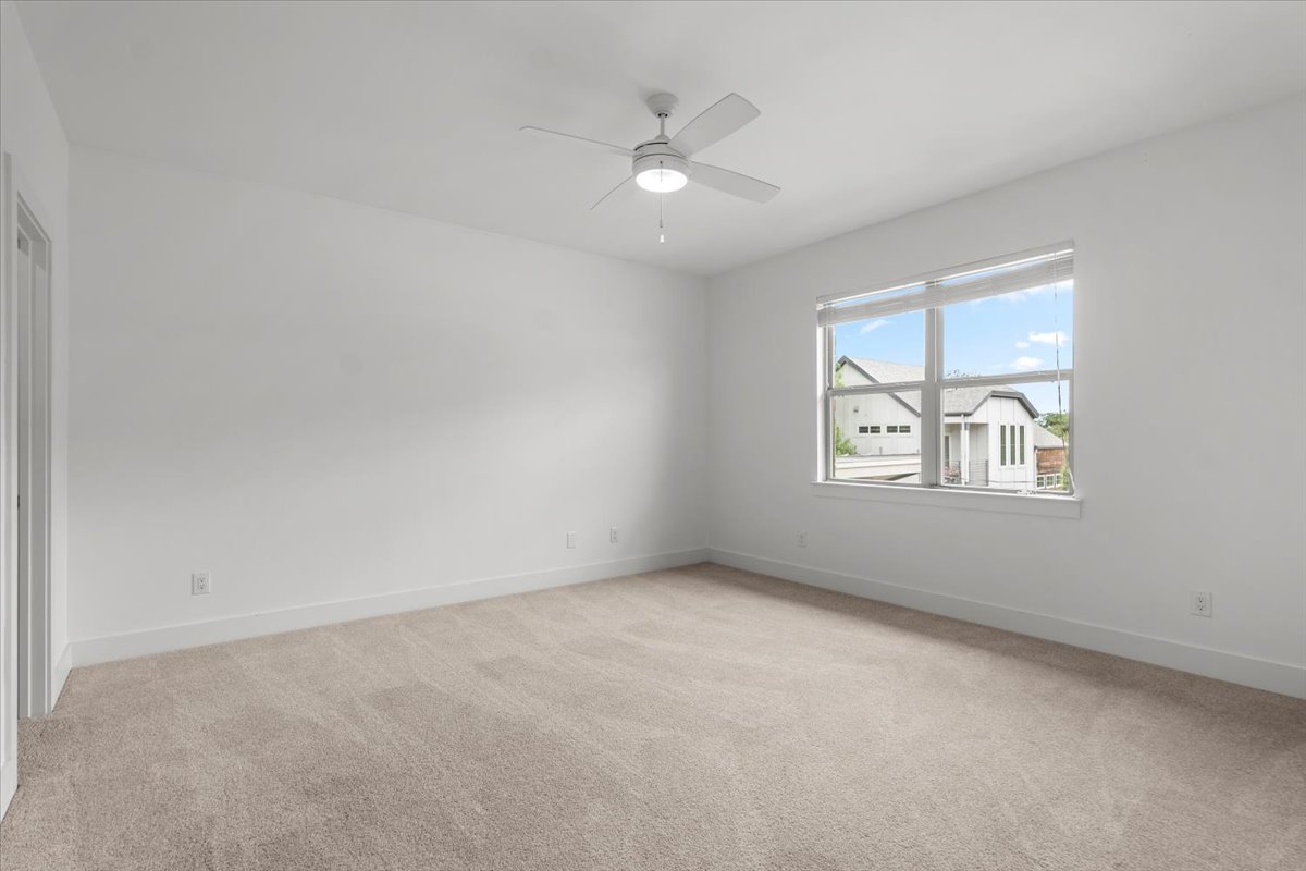 913 Stobaugh Street, Unit B Austin, TX 78757 - Photo 36 of 40 A spacious, naturally illuminated 3rd bedroom features plush carpeting and a modern ceiling fan.