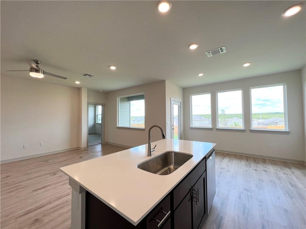 10600 Defender Trail Austin, TX 78754 - Photo 21 of 21 Kitchen featuring open floor plan, a center island with sink, light wood-type flooring, dark cabinetry, and recessed lighting