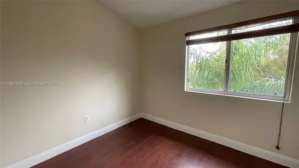 an empty room with wooden floor and a window
