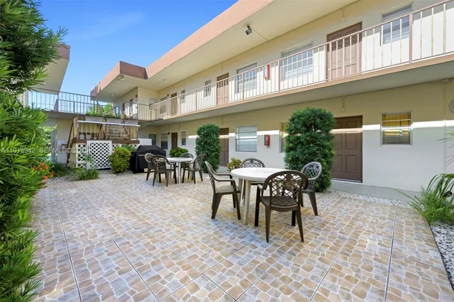 a patio with table and chairs and potted plants