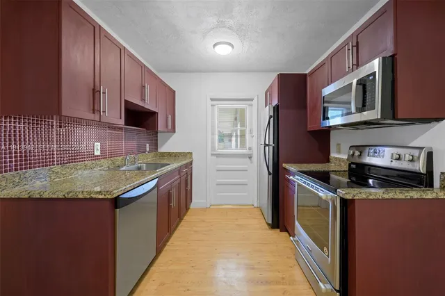 a kitchen with stainless steel appliances granite countertop a stove a sink and a microwave