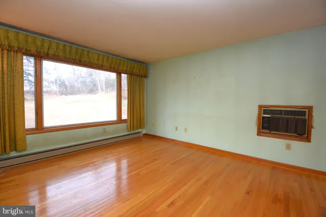 a view of an empty room with a window and wooden floor