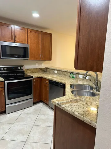 a kitchen with stainless steel appliances granite countertop a stove a sink and a microwave