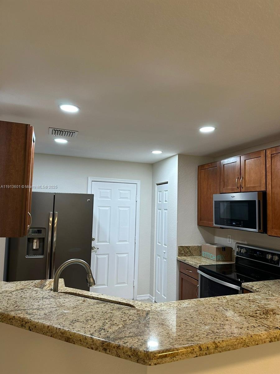 9113 Chambers Street Tamarac, FL 33321 - Photo 3 of 13 a kitchen with stainless steel appliances kitchen island granite countertop a refrigerator and a stove top oven