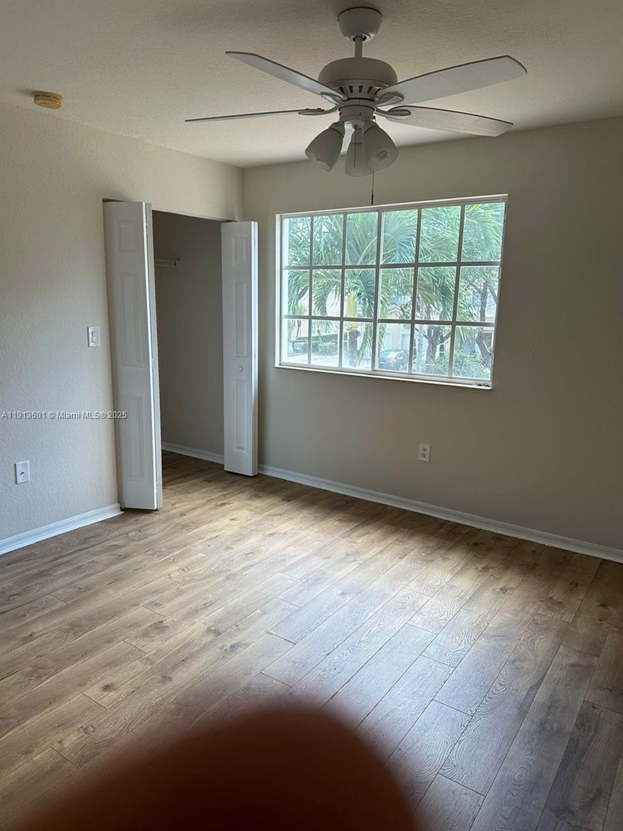 9113 Chambers Street Tamarac, FL 33321 - Photo 7 of 13 an empty room with wooden floor fan and windows