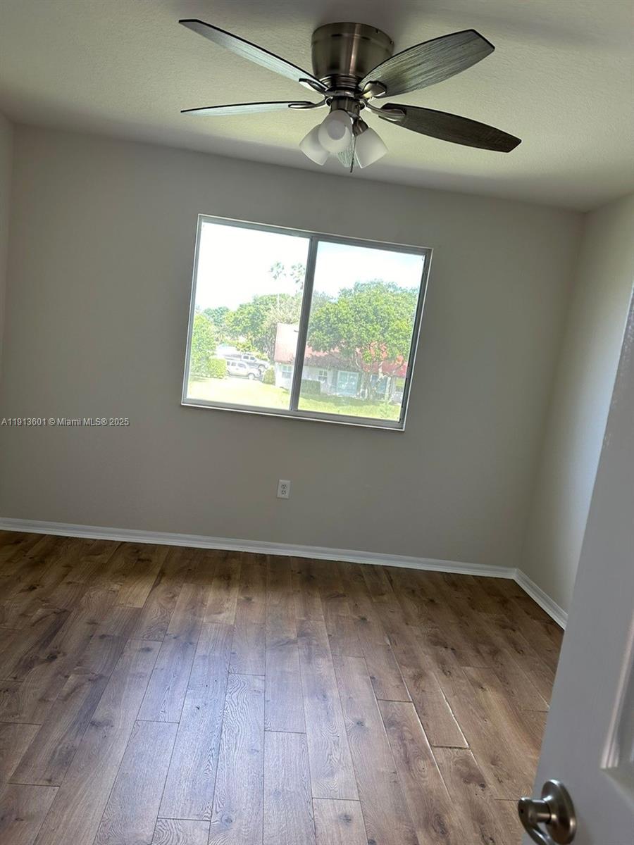 9113 Chambers Street Tamarac, FL 33321 - Photo 9 of 13 an empty room with wooden floor fan and windows