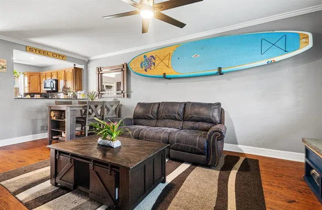 a living room with stainless steel appliances kitchen island granite countertop furniture and a wooden floor
