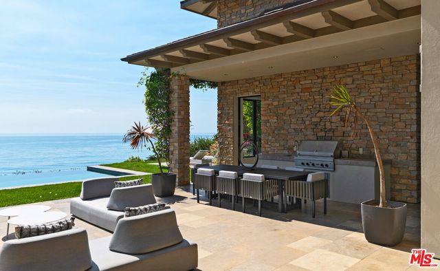 a patio with couches and a fire pit with wooden floor