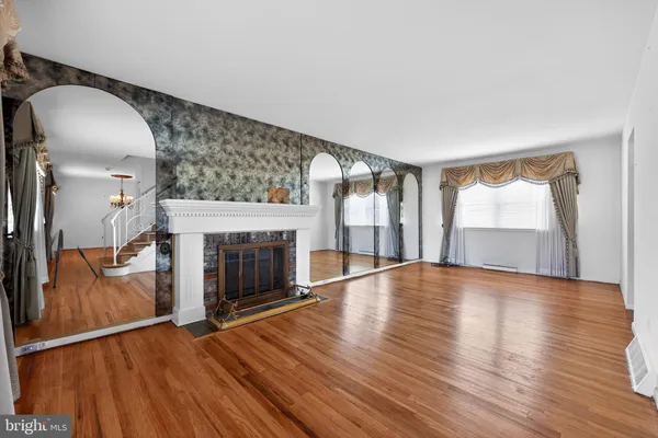 an empty room with wooden floor fireplace and windows