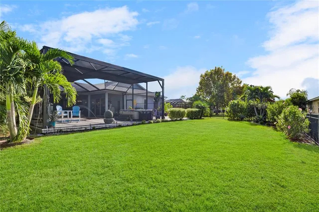 a backyard of a house with table and chairs plants and large trees