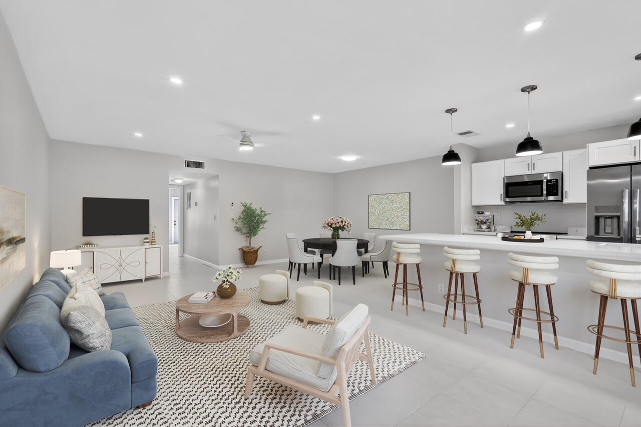 a living room with furniture a flat screen tv and kitchen view