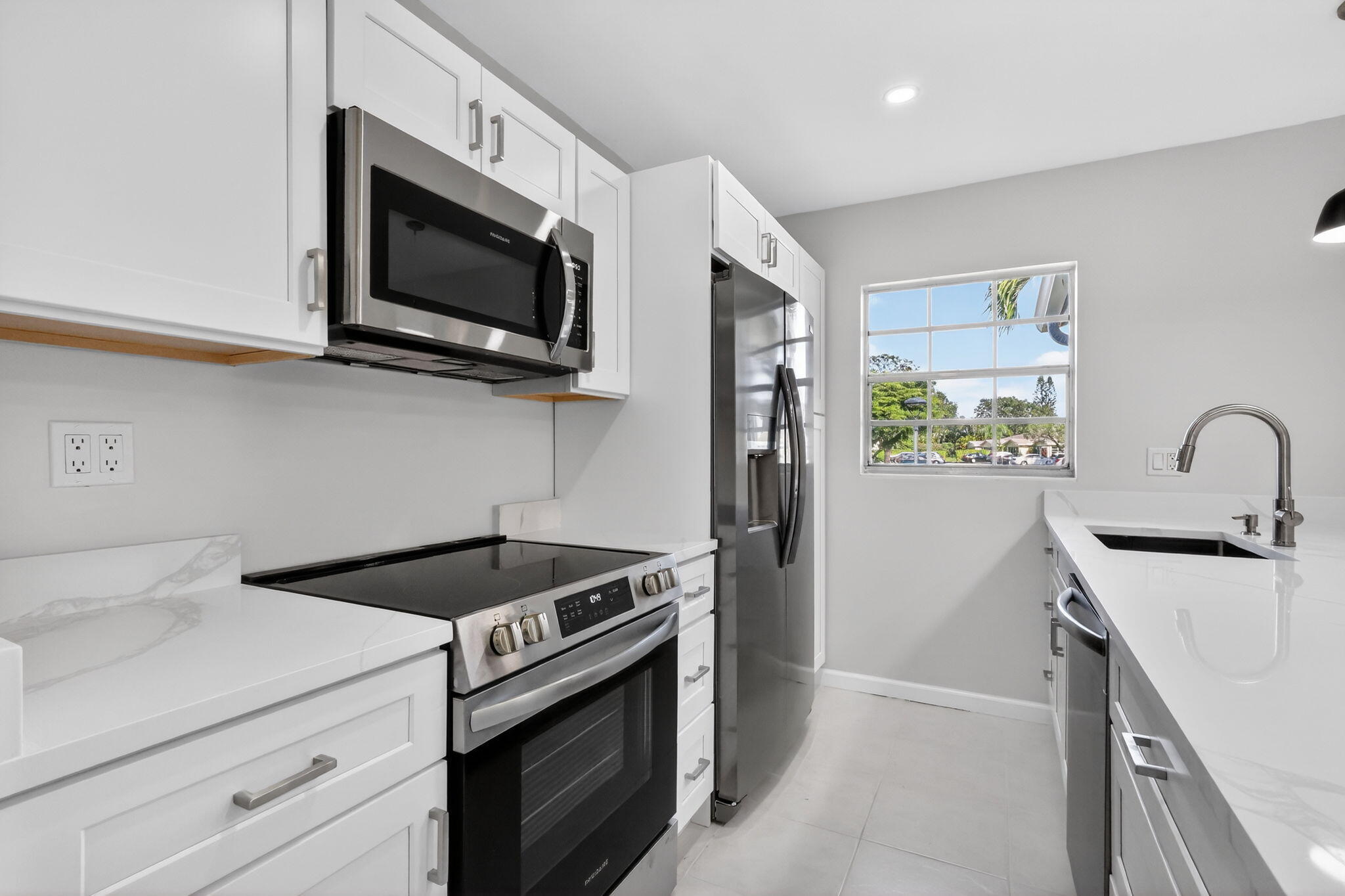 14280 Nesting Way, Unit B Delray Beach, FL 33484 - Photo 11 of 43 a kitchen with stainless steel appliances granite countertop white cabinets a stove top oven a sink and dishwasher