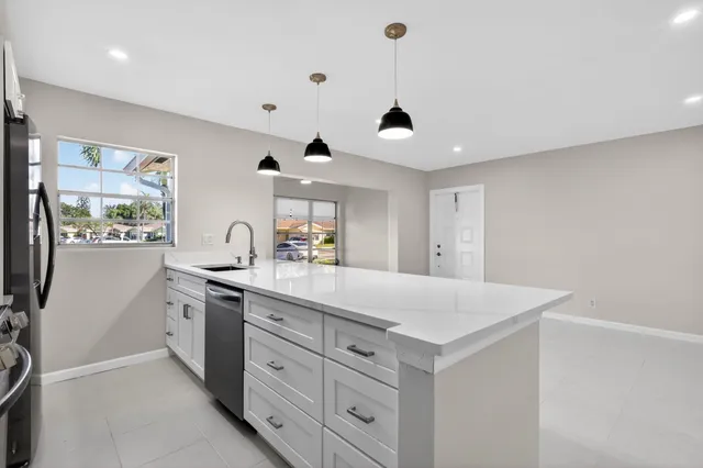 a kitchen with white cabinets and sink