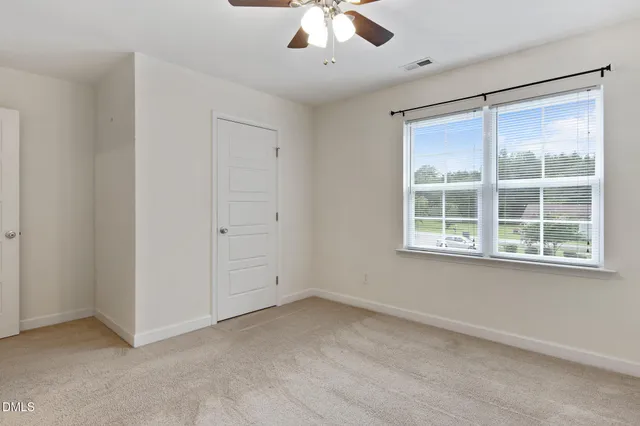 an empty room with a window and a ceiling fan