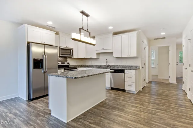 a kitchen with stainless steel appliances granite countertop a refrigerator a sink dishwasher a stove and a microwave oven on granite countertops