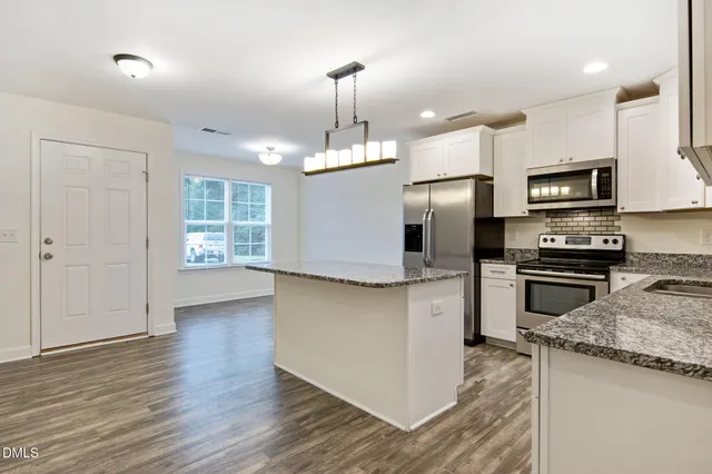 a kitchen with kitchen island granite countertop stainless steel appliances cabinets a sink and a center island