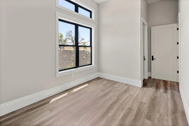 an empty room with wooden floor and windows