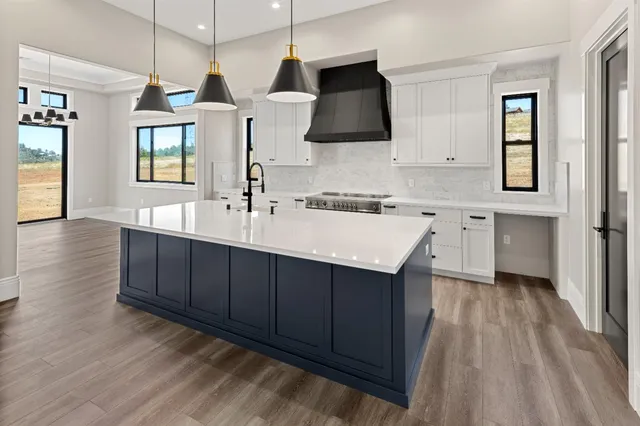 a kitchen with stainless steel appliances a sink stove and wooden floor