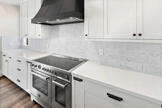 a kitchen with granite countertop a sink a stove and cabinets