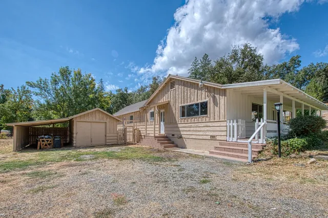 a view of a house with a yard and large tree