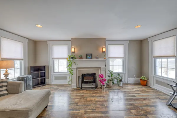 a view of a livingroom with a fireplace a window and wooden floor