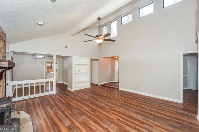 a view of an empty room with a window and wooden floor