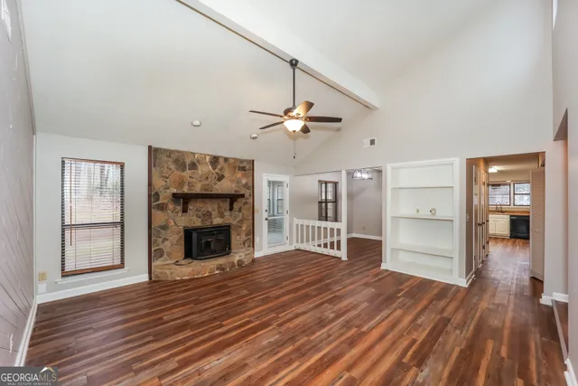 an empty room with wooden floor fireplace and windows