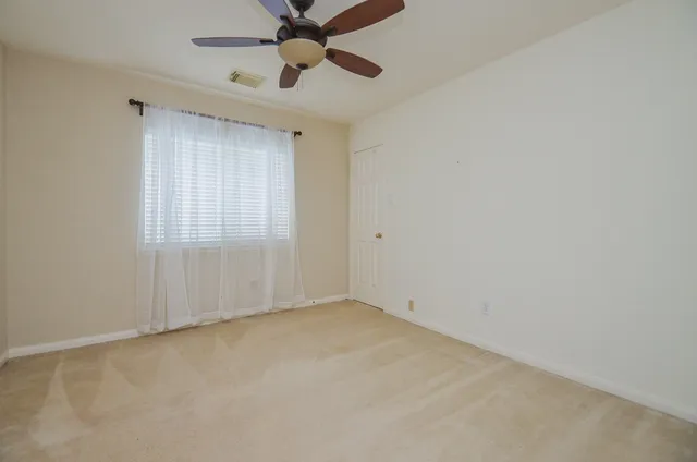 an empty room with a window and a fan