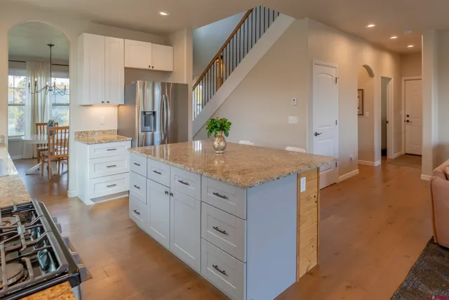 a kitchen with stainless steel appliances granite countertop a stove a sink a microwave a refrigerator and white cabinets