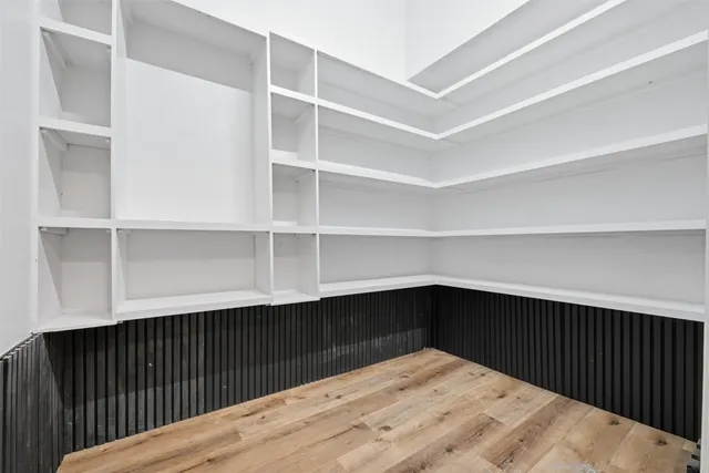 a view of an empty room with wooden floor and window