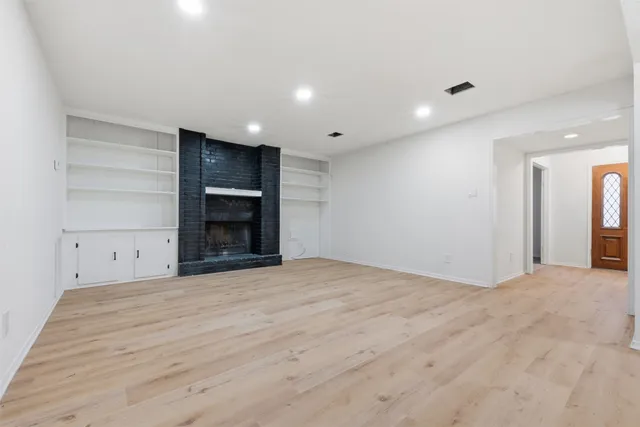 a view of an empty room with a fireplace and cabinet