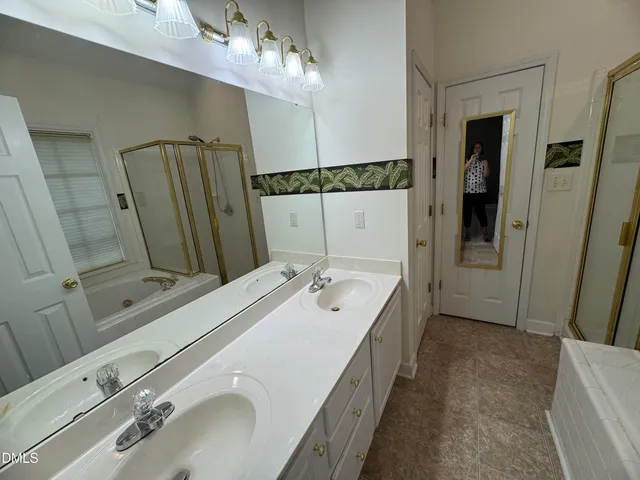 a spacious bathroom with a double vanity sink a mirror and shower