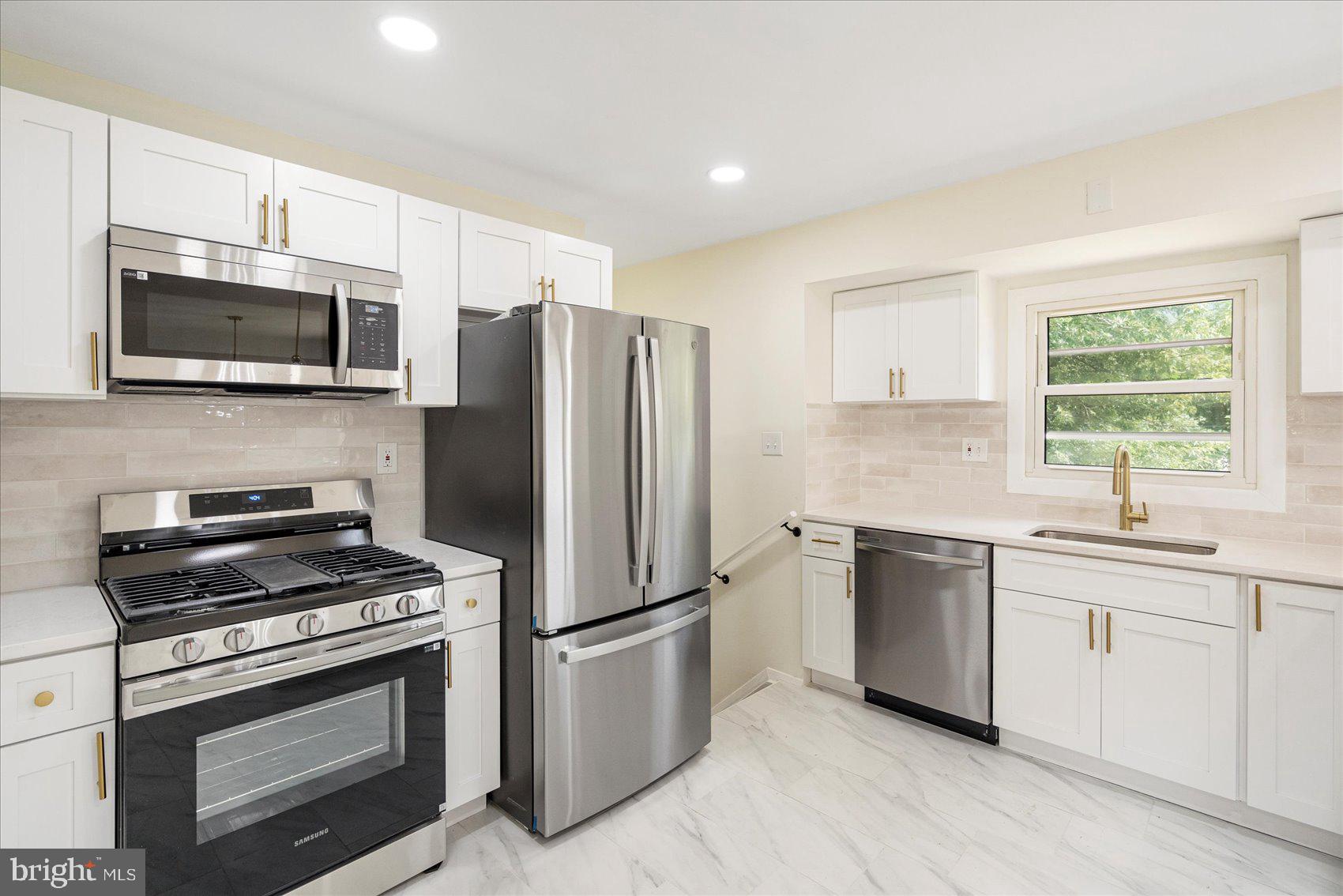 6726 Longhill Road Baltimore, MD 21207 - Photo 15 of 36 a kitchen with cabinets stainless steel appliances a sink and a window