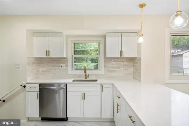 a kitchen with a sink dishwasher a stove and white cabinets with wooden floor