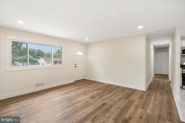 an empty room with wooden floor and windows