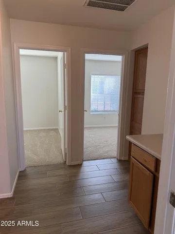 an empty room with wooden floor and a hallway