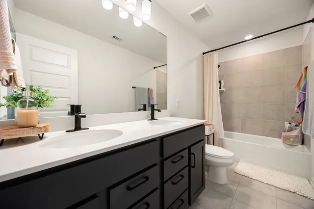 a bathroom with a double vanity sink toilet mirror and shower