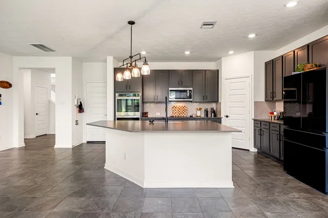a large kitchen with granite countertop a large counter top stainless steel appliances and cabinets