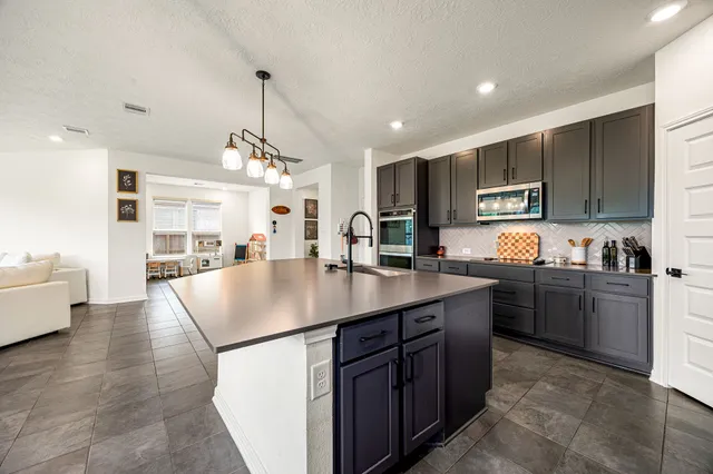 a kitchen with kitchen island granite countertop a sink a counter top space appliances and cabinets