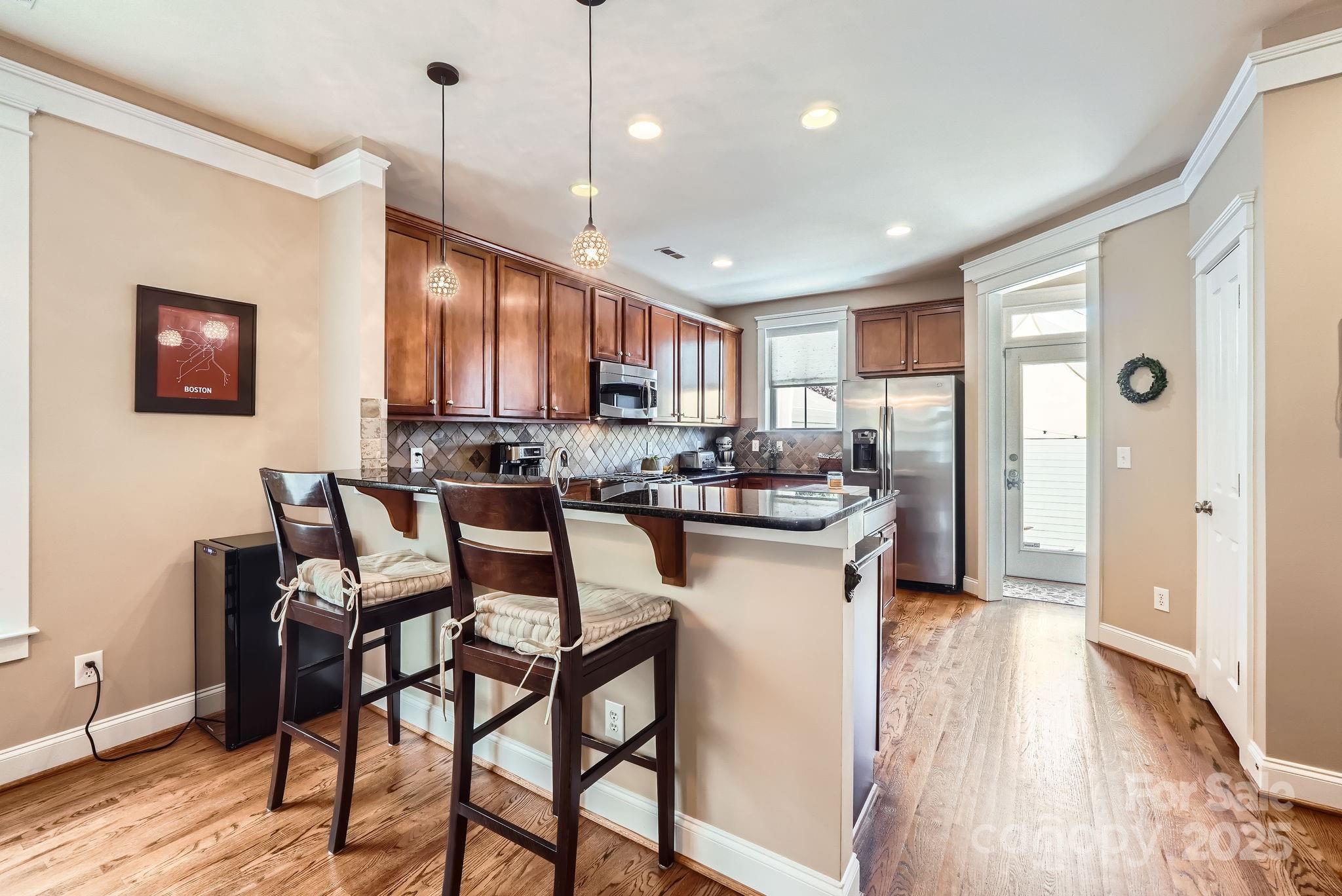 275 Bridges Farm Road Mooresville, NC 28115 - Photo 15 of 48 a kitchen with stainless steel appliances granite countertop a stove top oven a refrigerator a sink and a dining table with wooden floor