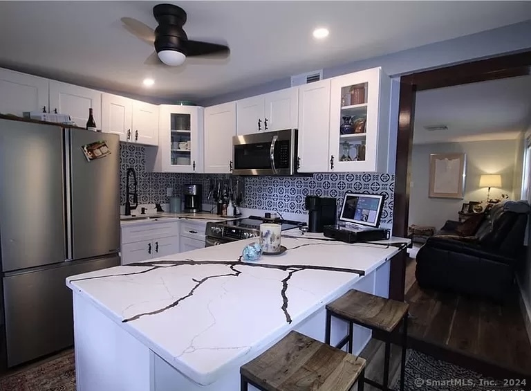 a kitchen with a refrigerator a counter top space a sink and chairs