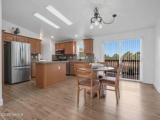 a kitchen with stainless steel appliances a dining table chairs refrigerator and microwave
