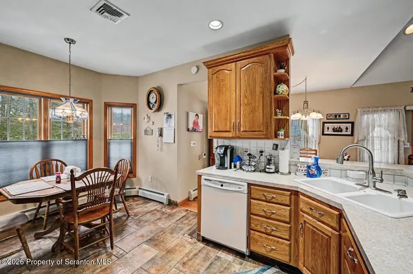 a kitchen with stainless steel appliances granite countertop a stove a sink dishwasher and a dining table with wooden cabinet